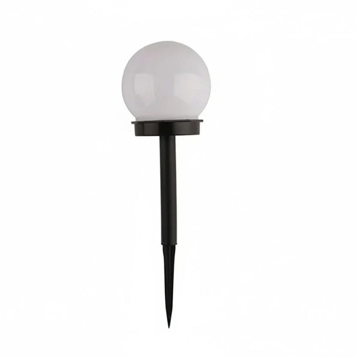Modern globe solar LED garden stake light in a landscaped garden bed