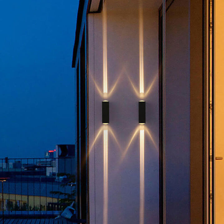 Modern rectangular LED outdoor wall sconce lit on a house facade