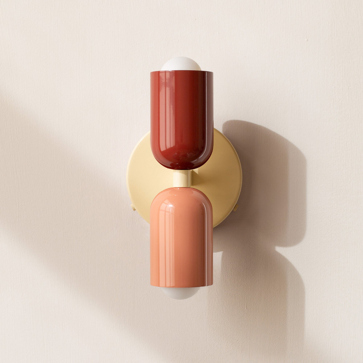 Minimalist cylinder LED wall sconce in red and beige throwing light up and down a feature wall