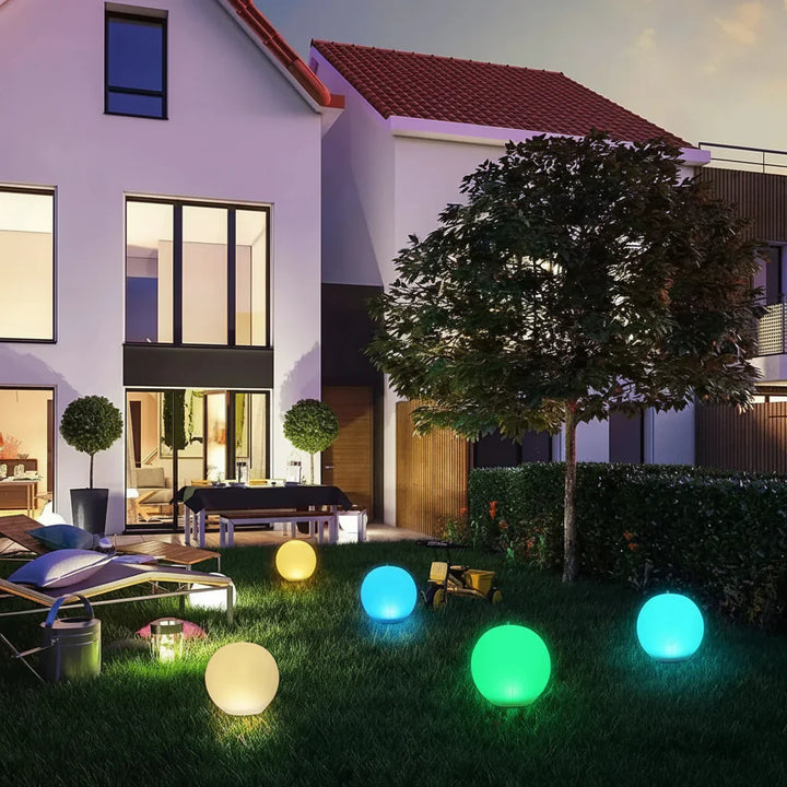 Modern globe solar LED floating light glowing on a still garden pond at night