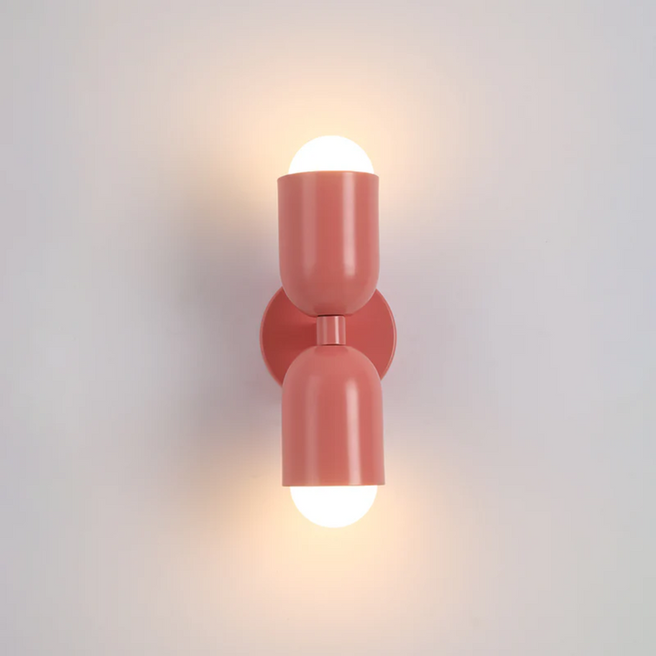 Pink double-sided LED cylinder wall lamp installed in a contemporary studio