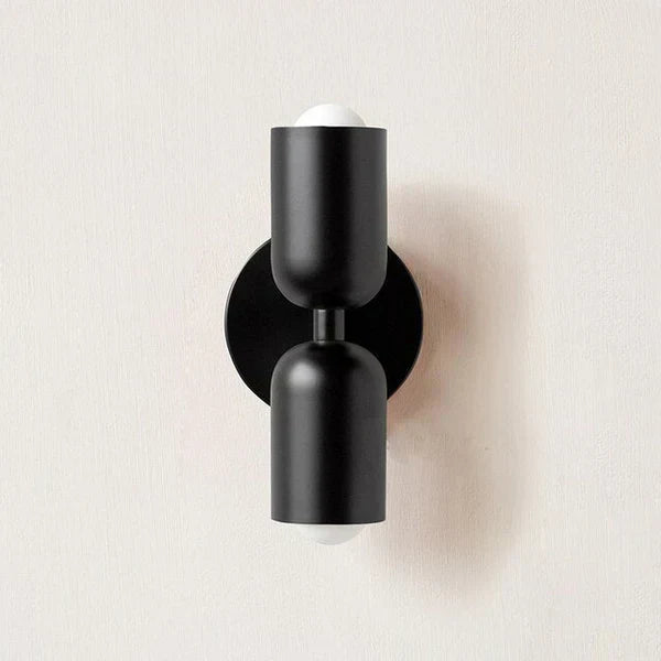 Black 2-light up-down cylinder LED wall sconce in a contemporary bedroom