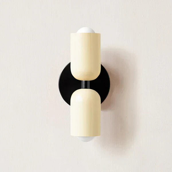DualGlow LED metal cylinder wall sconce in white throwing twin light beams on a textured wall