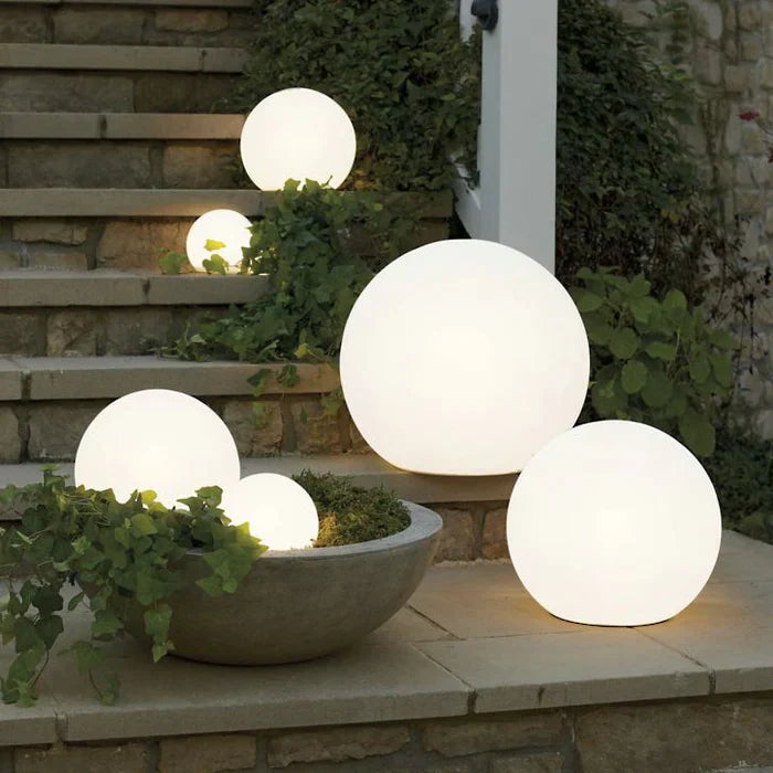 Modern PE globe garden light glowing on patio at dusk